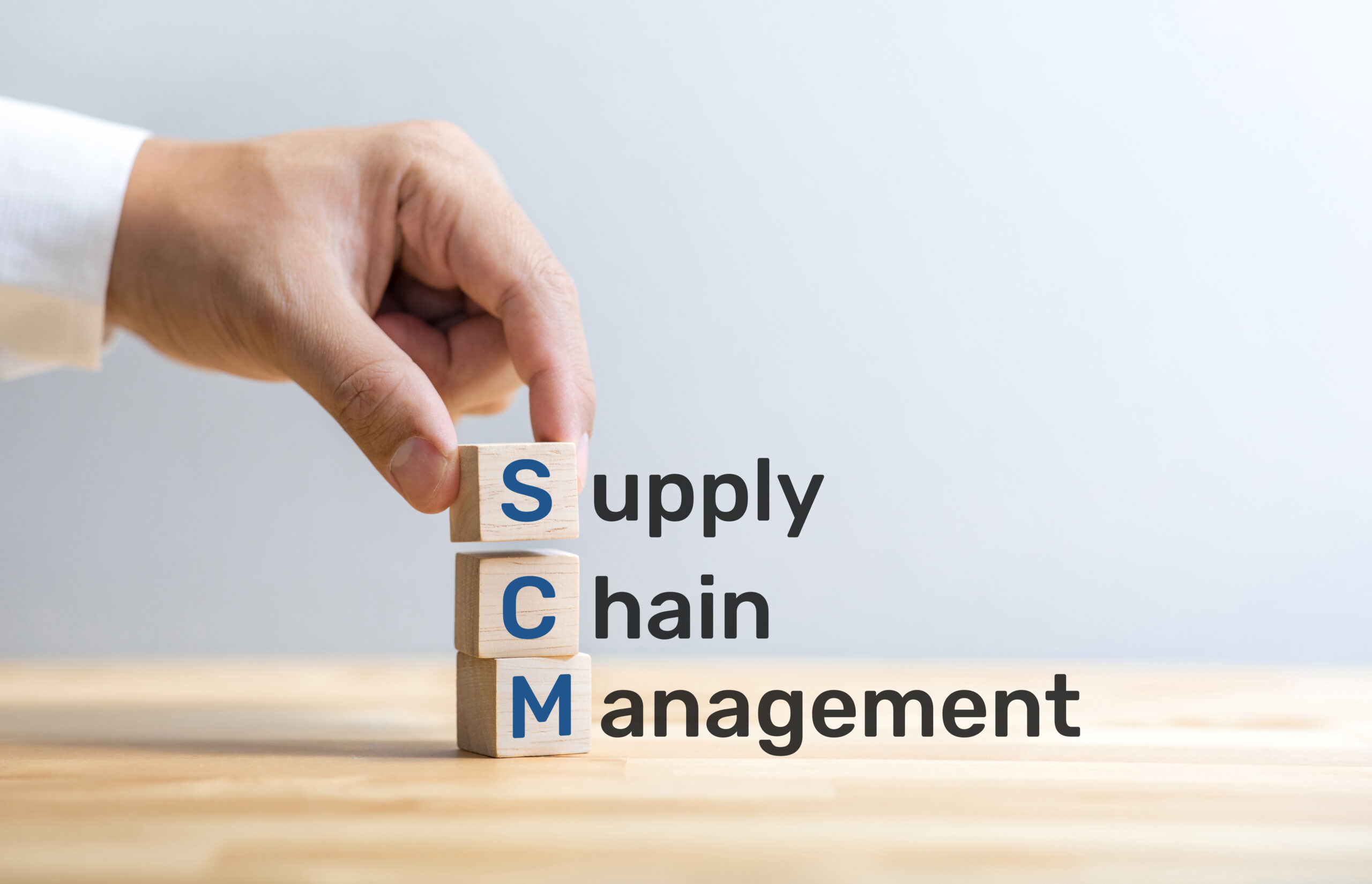 SCM text on wood box with male hand.business and industry manag